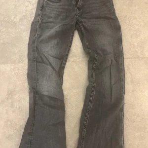 Grå jeans från Gina Tricot, stl 140 - Snygga grå jeans från Gina Tricot i storlek 140. Jeansen är ganska low waist och klassisk femficksdesign med coola detaljer på bakfickorna. Perfekta för dig som gillar en avslappnad och stilren look som ändå är trendig.