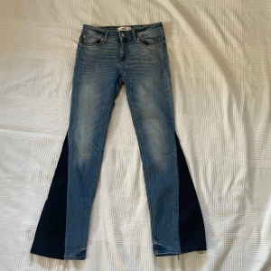Blå bootcut jeans från Mango, strl 36 - blåa och lågmidjade  jeans från Mango i storlek 36 med bootcut och svarta kilar i benen.