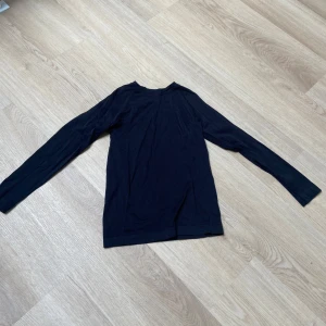 Svart underställs tröja  - En enkel svart underställs tröja med rund hals. Tröjan har en smal passform och är tillverkad i ett mjukt material som känns skönt mot huden. Perfekt att ha på vinter under någon tröja eller om du tränar.