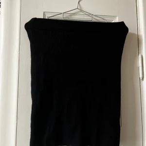 Svart stickad kjol från Amisu(kan användas som en tubtopp om det så önskas) - Svart, ribbstickad kjol från Amisu i storlek 34. Kjolen har en enkel, figurnära form och är kort i modellen. Perfekt för dig som gillar minimalistisk stil och vill ha en basic kjol som funkar till många olika looks.