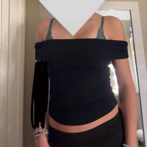 Svart offshoulder topp Gina Tricot - Säljer en marinblå offshoulder topp från Gina Tricot. Toppen är tight och croppad med axelbandslös design som ger en snygg och stilren look. Perfekt att matcha med jeans eller kjol för en trendig outfit.