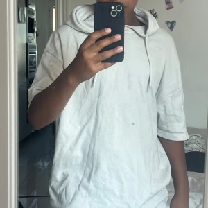 Vit hoodie med kort ärm från FSBN - Säljer en vit hoodie från FSBN i loose fit med korta ärmar och huva med snörning. Tröjan är tillverkad i mjuk bomull och har en clean, enkel look som passar perfekt till chill dagar. Oversized känsla och riktigt skön att bära.