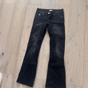 Svarta bootcut jeans Gina Tricot - Svarta jeans från Gina Tricot i bootcut-modell med snyggt utsvängda ben. Klassisk femficksdesign, silverfärgade knappar och detaljer. Jeansen är i stretchigt denimtyg och har normal passform. Perfekta för en cool och avslappnad look.