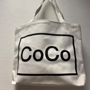 Tyg Väska  - Två stilrena väska från CoCo, en i vitt med svart tryck och en i svart med vitt tryck. Väskorna har rejäla handtag och är tillverkade i bomull. Perfekta för att bära med sig allt man behöver under dagen. Helt ny  . 99kr/st 