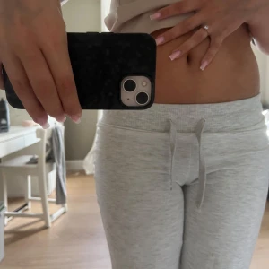 Grå mjukisbyxor från Gina Tricot - Supermysiga ljusgrå mjukisbyxor från Gina Tricot i storlek S. De har bred resår i midjan med snörning och ett loose fit med raka ben. Perfekta för chill dagar hemma eller när du vill vara extra bekväm. Materialet är mjukt och skönt bomullstyg.