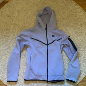 Ljuslila Nike tech  - Nike tech i ljuslila med svart dragkedja och detaljer. Snygg, stilren och använd fåtal gånger.  Priset kan diskuteras