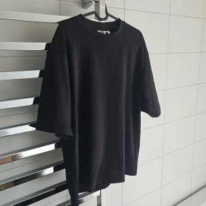 Svart oversized t-shirt Uniqlo - Svart t-shirt med loose och oversized passform, rund hals och korta ärmar. Enkel och clean design utan mönster eller detaljer, perfekt för dig som gillar minimalistisk stil. Materialet känns mjukt och bekvämt, troligtvis bomull. Tishan är från uniqlo, väldigt snygg och absolut den skönaste tishan jag äger. Säljes då jag ska gå upp en storlek. Inget riktigt tecken på användning men har använt den så kan inte säga nyskick.