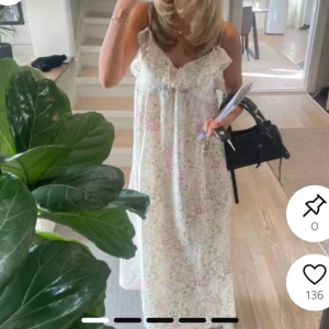 Lång blommig sommarklänning med volang - Superfin långklänning i ljusa färger med blommigt mönster. Klänningen har smala axelband, volangdetalj vid bysten och en luftig passform. Perfekt för varma dagar och ger en romantisk vibe.