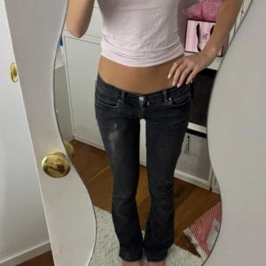 Svarta bootcut jeans låg midja - Snygga svarta jeans med bootcut och låg midja. Jeansen har en klassisk femficksmodell och lätt slitna detaljer framtill. Perfekta för dig som gillar en avslappnad men trendig look. Sytt in jeansen så att de blir lågmidjade själv!