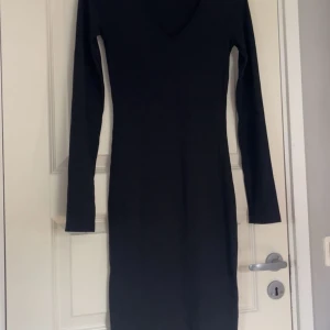Svart ribbad långärmad långklänning💕 - En svart, ribbad långärmad klänning med v-ringning. Även fin slits detalj på armarna. Helt oanvänd utifrån när jag provat den💓 Rätt så lång men inte så att den täcker hela kroppen🙌🏼Hel svart men ljuset blev lite konstigt på sista bilden.