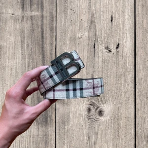 Burberry bälte  - Tre snygga Burberry-bälten med ikoniskt rutigt mönster och stor metallfärgad B-logga som spänne. Finns i ljusgrått, svart och marinblått. Bältena är tillverkade i skinn och har klassisk, stilren design som sticker ut. Priset är ej fast kom med bud 
