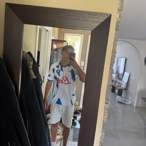Napoli fotbollströja EA7 blå/vit - Säljer en Napoli fotbollströja från EA7 i vitt med blåa grafiska detaljer och röda logotyper. Skön tröja med bra kvalité, helt oanvänd 