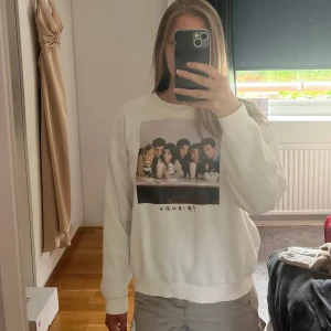 Vit Friends-tröja  - Vit sweatshirt från H&M med stort Friends-tryck framtill. Tröjan har rund hals, långa ärmar och ribbade muddar. Efter många tvättar har materialet från insidan blivit lite noppigt, men tröjan är fortfarande bekväm att ha på sig 🥰trycket har även börjat suddas ut lite men syns fortfarande tydligt, vilket syns på bilderna 💗