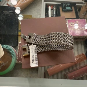 Silvrigt armband från Edblad - Snyggt och brett armband från Edblad i flätad design. Armbandet är i silverfärgad metall och har ett coolt, robust spänne med märkets logga ingraverad. Perfekt accessoar för att lyfta din outfit med en modern touch.