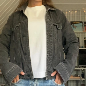 Svart jeansjacka f - Säljer en svart jeansjacka från Mango med klassisk krage, knäppning framtill och två bröstfickor. Jackan har en rak passform och är i  denimtyg. Den är i storlek L men sitter som en S/M