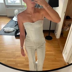 Ljusgrå byxdress med bustierliv - Säljer helt nytt sett topp och byxor så tröjan satt för tight på mig och ville gärna ha båda delar. Prislapp kvar!