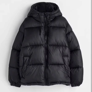 pufferjacka med huva - Säljer en svart pufferjacka med oversized passform och huva. Jackan har dragkedja framtill, två sidofickor och breda kanaler för en riktigt puffig look. Köpt i vintras men kom till användning max 5 gånger, större i storlek 