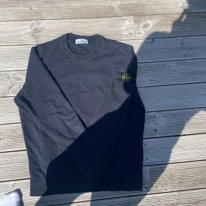 Marinblå  långärmad tröja Stone Island - Svart långärmad tröja från Stone Island med klassisk rund hals och ikonisk logotyp-patch på vänster ärm. Tröjan är i storlek XL, men Stone Islands storlekar är alltid en storlek för liten så tröjan sitter 100% som en L. Tröjan är i fint skick!