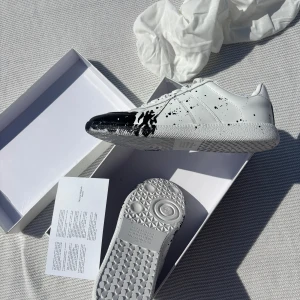 Maison margielas  - Hej säljer nu dessa maison margielas i helt nytt skick. Skorna är aldrig använda. Färgen är vit med svart färg stänk. Storlek 43 kom gärna med prisförslag och frågor !