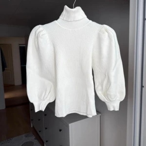 Stickad tröja med polokrage - Tröja med polokrage och puffärmar som slutar vid armbågen, antingen över eller under armbågen beroende på hur man vill bära tröjan. 