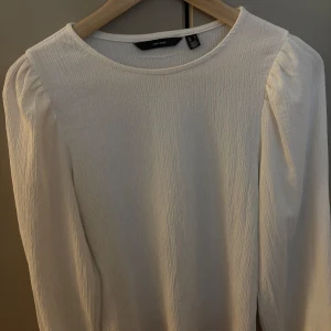 Vit blus med puffärm från Vero Moda - Supersöt vit blus från Vero Moda i storlek S. Blusen har långärmade puffärmar och är gjord i ett lätt strukturerat tyg. Bra skick och knappt använd.