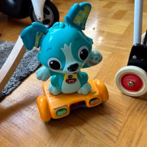 Hoverboard-valp - Det här är ingen bok, utan en interaktiv leksak från VTech! Hoverboard-valpen är en färgglad, söt hund på hjul som spelar musik och lär ut siffror. Perfekt för yngre barn som gillar att leka och lära sig på ett roligt sätt.