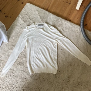 Vit stickad tröja från 157, storlek S - Klassisk vit stickad tröja från 157 i storlek S. Tröjan har rund halsringning, långa ärmar och ribbade muddar vid hals, ärmslut och nederkant. Perfekt för lager-på-lager och enkel att matcha med jeans eller kjol. Har en tajspassform. Säljer då den inte kommer till använd längre, samt att den är lite tight på mig tyvärr! Perfekt till sommarkvällar då den är hyfsat tunn i materialet. 💕👌🏼
