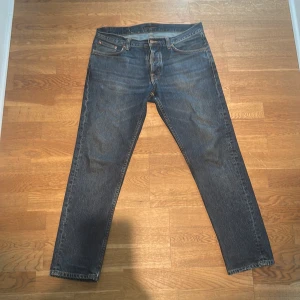 Mörkblå jeans från Nudie Jeans - Säljer ett par mörkblå jeans från Nudie Jeans med klassisk femficksdesign och snygga kontrastsömmar. Jeansen är modellen Steady Eddie ll. 