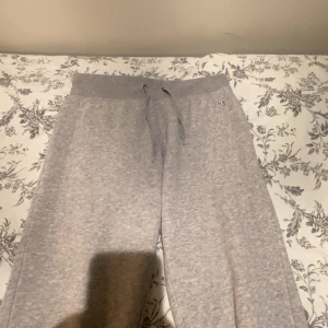 Grå mjukisbyxor från Champion S - Grå mjukisbyxor från Champion i storlek S. Byxorna har bred resår i midjan med snörning och muddar vid bensluten. Perfekta för chill eller träning, med diskret Champion-logga på höften. Mjukt material som känns skönt mot huden.