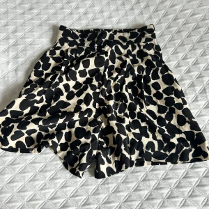 Svartvita leopardmönstrade shorts från H&M - Säljer svartvita shorts från H&M med leopardmönster. Shortsen har hög midja och är i en kort modell med lätt utställd form. Perfekt för dig som vill sticka ut med ett djurmönster!