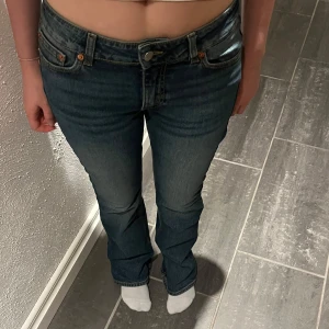 Blå bootcut jeans - Säljer ett par klassiska blå bootcut jeans från Junkyard med snygga kontrastsömmar och femficksmodell. Jeansen har normal passform och är tillverkade i ett slitstarkt denimtyg. Perfekta för dig som gillar en tidlös stil.