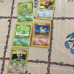 Pokémonkort - Caterpie, Jigglypuff, Oddish, Ponyta, Tyrogue - Fem Pokémonkort säljes: Caterpie (grön), Jigglypuff (rosa), Oddish (grön), Ponyta (orange/röd) och Tyrogue (rosa/lila). Klassiska samlarkort med färgglada illustrationer och Pokémon-typ, attackpoäng och beskrivningar på varje kort. Priset kan diskuteras 