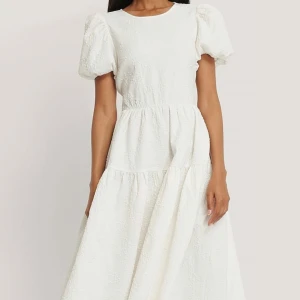 Vit långklänning med puffärm och rosetter - Superfin vit långklänning från Nakd. Säljer då den är lite för kort för mig som är 178 cm🤍Strl 34 men skulle säga att den passar mig som vanligtvis är en s/m. 