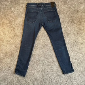 Mörkblå jeansbyxor från Replay - Skick 10/10 |storlek W32L30 finns ej bild med dessa på | Mått midja:40cm längd: 99cm | modell ”Anbass” | pris i butik:1600kr | frågor om mer mått fler bilder eller liknande är det bara höra av dig! | frakt sker via post nord eller instabox. Ignorera de bruna jag fick de så är nog bara lite dam tvättar i när jag postar