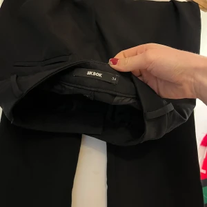 Svarta kostymbyxor från Bik Bok - Säljer ett par svarta kostymbyxor från Bik Bok i storlek 34. Perfekta för en stilren och klassisk look.