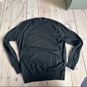 Mörkgrön merinoull tröja från Uniqlo - Säljer en stilren mörkgrön merinoull tröja från Uniqlo. Tröjan har rund halsringning och långa ärmar