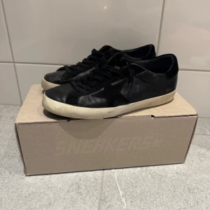Svarta sneakers från Golden Goose - Säljer ett par svarta Golden Goose Super-Star sneakers med vit sula och svart stjärndetalj på sidan. 