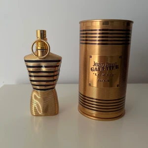 Jean Paul Gaultier Le Male Elixir 65ml - Exklusiv herrparfym i en lyxig guld- och svart randig flaska formad som en manlig torso. Kommer med matchande guldig metallburk och röd sammetsbas. Doften är intensiv och modern, perfekt för dig som vill sticka ut. Cirka 60-65ml kvar 