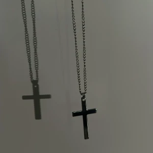 Silverfärgat korshalsband - Stilrent halsband med ett kors i silverfärg. Kedjan är tunn och korshänget har en enkel, modern design. Perfekt för dig som gillar minimalistiska smycken.