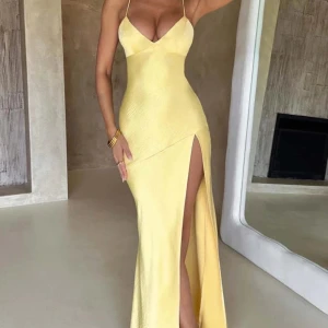 Gul balklänning med slits och öppen rygg - Säljer en elegant gul långklänning med smala axelband, djup slits framtill och öppen rygg med snörning. Klänningen har en figurnära passform och är perfekt för sommarens fester eller bal. Passar S eller XS, aldrig använd då den var för stor för mig🥰