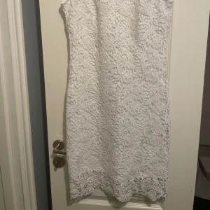 Vit spetsklänning perfekt för studenten  - Säljer en elegant vit spetsklänning med vackert mönster och ärmlös design. Klänningen har en rak passform och är perfekt för somriga tillfällen som student eller midsommar. Fodrad under spetsen för extra komfort. 