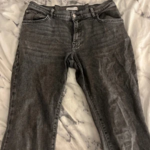 Grå jeansbyxor med bootcut - Säljer ett par grå jeansbyxor med klassisk femficksdesign och bootcut. Byxorna har normal passform och stängs med dragkedja och knapp. Perfekta till vardags för en avslappnad stil. Har sytt in 4cm!!!!