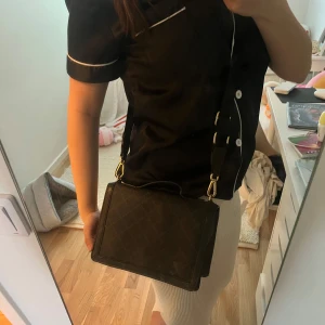Malene Birger Axel väska  - Säljer en svart axelväska med rutigt mönster och guldfärgade detaljer. Väskan har justerbar axelrem, topphandtag och dragkedja på baksidan. Perfekt för att bära det viktigaste i vardagen. Original pris runt 3000. Lite fläckar men syns knappast endast med blixt på.