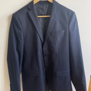 Mörkblå kostym - Säljer en klassisk mörkblå kostym från Selected Homme. Använd vid enstaka tillfällen och är i mycket bra skick. Hör av dig vid frågor! Storlek 42 i kavajen och storlek 44 i byxorna. 