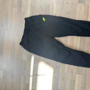 Nike techfleece med gul logga  - Svarta nike tech fleece byxor med gul logga, knappast använda. Nypris runt 1000kr. Vid snabb affär kan jag gå ner i pris . Storlek M men passar S också. 