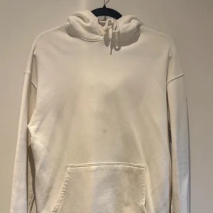 Vit hoodie från Junkyard - Säljer en enkel och stilren vit hoodie från Junkyard i storlek S. Tröjan har huva med dragsko och en stor magficka framtill. Perfekt för en avslappnad och bekväm stil. Fläckig vid kragen och lite på magen