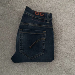 Dondup jeans - Säljer ett par mörkblå jeans från Dondup med klassisk femficksdesign och snygga kontrastsömmar. Jeansen har normal passform och raka ben. Perfekta för dig som gillar stilrena och tidlösa jeans. Storlek 29, äkthetsbevis från Vestiaire. 