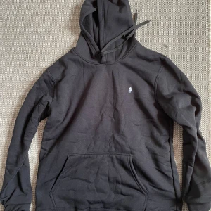 Svart hoodie från Polo Ralph Lauren - Säljer en svart hoodie från Polo Ralph Lauren med klassisk broderad logga på bröstet. Tröjan har huva med dragsko och en stor magficka. Perfekt för en avslappnad stil. Skriv för mer info eller fråga frågor🙏😀