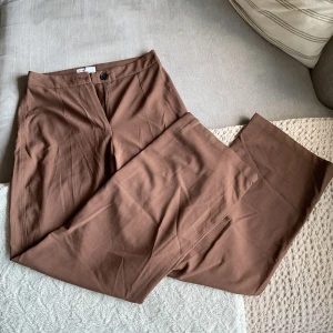 Bruna kostymbyxor från Bershka - Snygga bruna kostymbyxor från Bershka med hög midja och raka ben. I storlek 38 och sparsamt använda. 