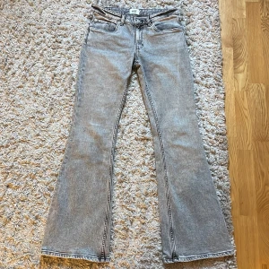 Grå bootcut jeans från lager 157 - Säljer ett par grå bootcut jeans från 157. Jeansen har klassisk femficksdesign, normal passform upptill och utsvängda ben. De är tillverkade i denim och har knapp- och dragkedjestängning framtill. Jeansen är knappt använda och i bra skick.